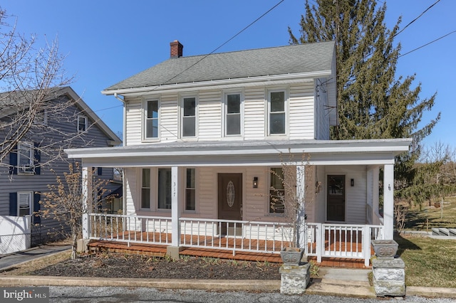 farmhouse featuring fence, covered porch, roof with shingles, and a chimney