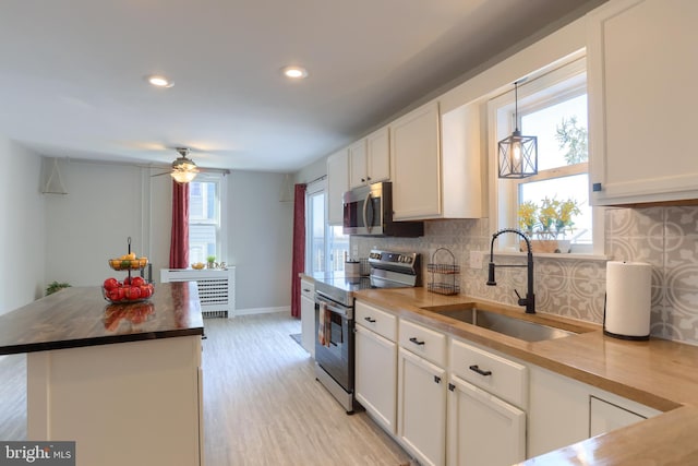 kitchen with tasteful backsplash, white cabinets, stainless steel appliances, and a sink