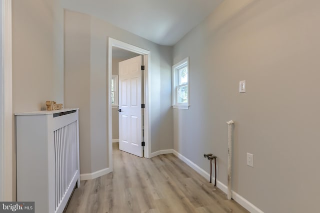 hallway with an upstairs landing, baseboards, and light wood-style flooring