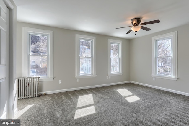 empty room with carpet flooring, a ceiling fan, radiator heating unit, and baseboards