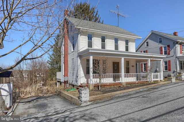 view of front of house featuring a shingled roof, a porch, and a chimney