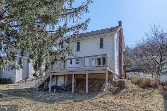 back of property with stairway, a deck, and a chimney