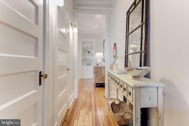 hall with built in shelves and light wood-type flooring