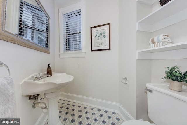 half bathroom featuring baseboards and toilet