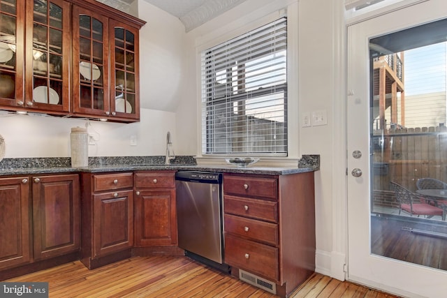 kitchen with visible vents, light wood-style flooring, glass insert cabinets, and stainless steel dishwasher