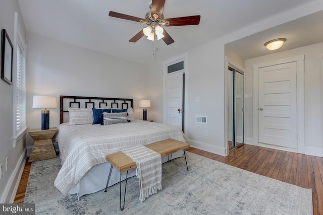 bedroom featuring visible vents, a ceiling fan, baseboards, and wood finished floors