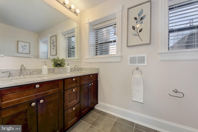 bathroom with tile patterned floors, double vanity, baseboards, and a sink