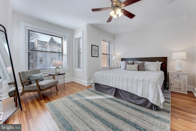 bedroom with a ceiling fan, baseboards, and wood-type flooring