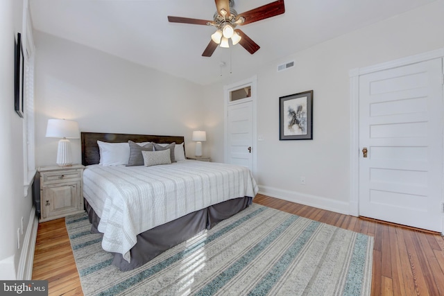 bedroom featuring visible vents, baseboards, light wood-style flooring, and a ceiling fan