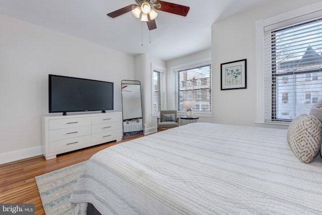 bedroom with a ceiling fan, radiator, wood finished floors, and baseboards