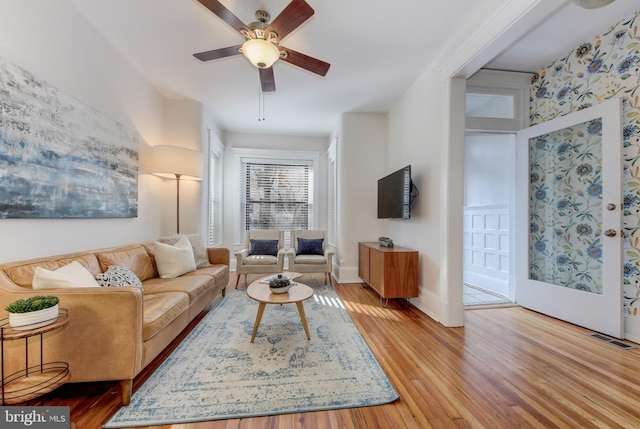 living room featuring light wood-type flooring, baseboards, visible vents, and a ceiling fan