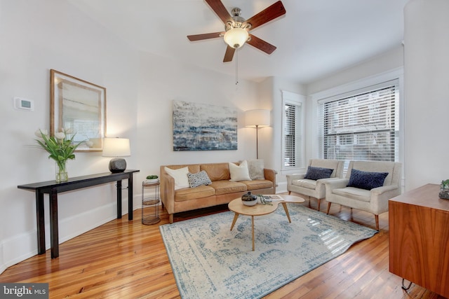 living area featuring ceiling fan, baseboards, and light wood-style floors