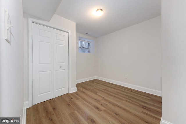 unfurnished bedroom with a closet, baseboards, and wood finished floors