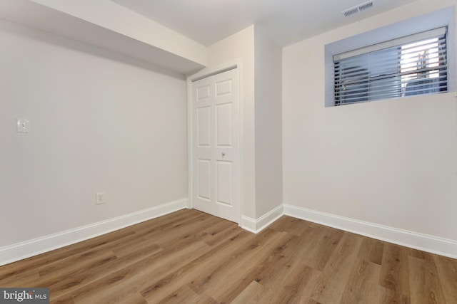 empty room featuring wood finished floors, baseboards, and visible vents