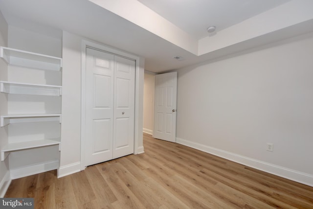 unfurnished bedroom featuring visible vents, wood finished floors, baseboards, and a closet