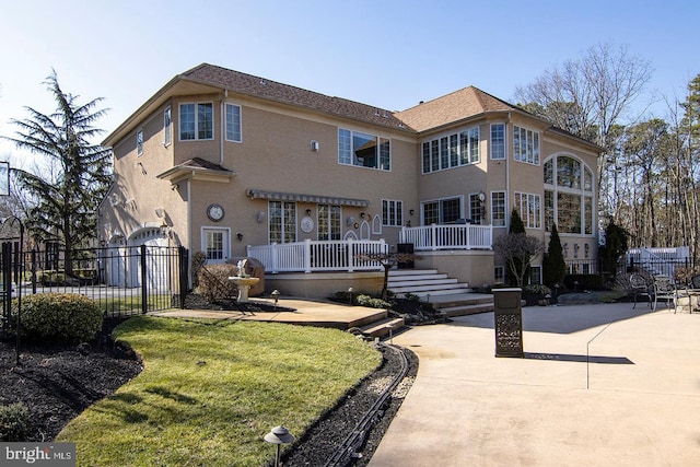 rear view of property featuring a patio, fence, a lawn, and stucco siding