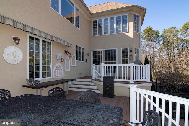 back of property featuring a wooden deck, outdoor dining space, and stucco siding