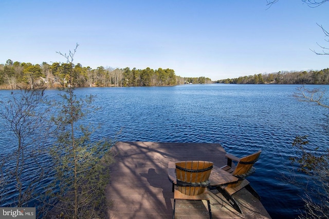 view of dock with a wooded view and a water view