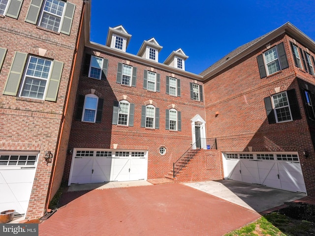 view of property featuring brick siding, driveway, and a garage