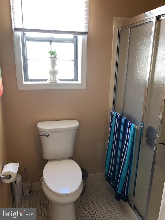 bathroom with tile patterned floors, toilet, and a stall shower