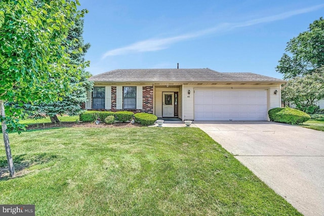 ranch-style house featuring brick siding, an attached garage, concrete driveway, and a front yard