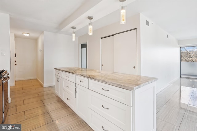 kitchen with hanging light fixtures, white cabinets, light stone counters, and visible vents