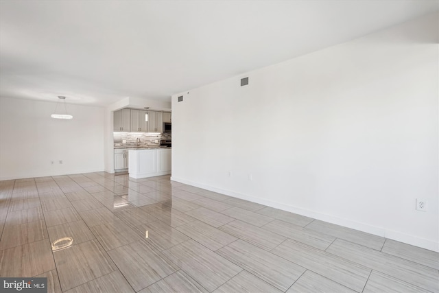 unfurnished living room with baseboards and visible vents