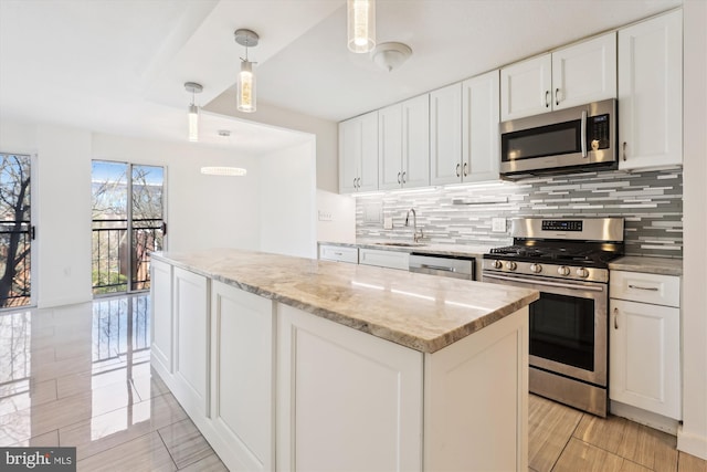 kitchen featuring backsplash, a center island, appliances with stainless steel finishes, white cabinets, and a sink