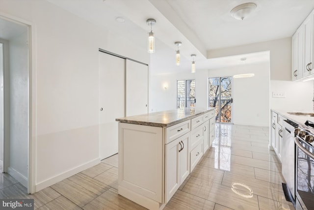 kitchen with pendant lighting, light stone counters, a kitchen island, stainless steel stove, and white cabinets