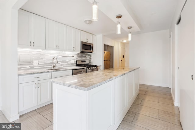 kitchen featuring tasteful backsplash, white cabinetry, stainless steel appliances, and a sink