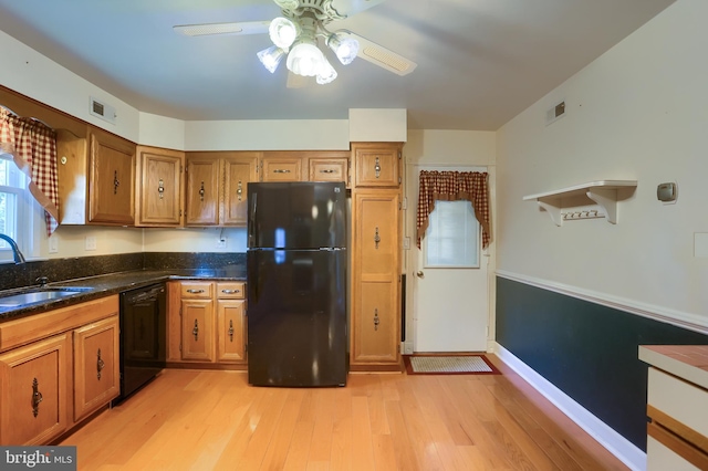 kitchen with brown cabinetry, visible vents, black appliances, and a sink