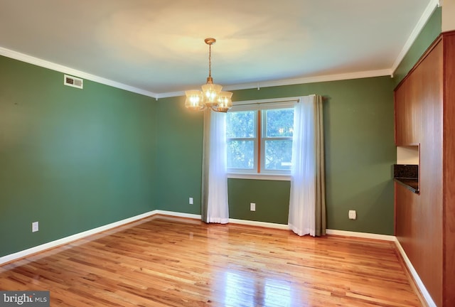 unfurnished dining area featuring crown molding, light wood-type flooring, and baseboards