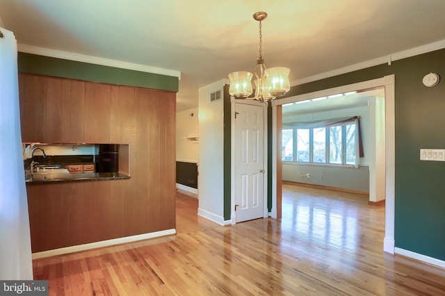 unfurnished dining area featuring baseboards, visible vents, light wood finished floors, and a chandelier