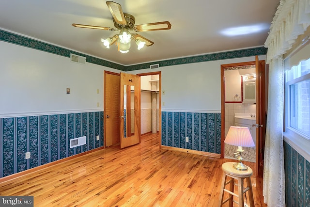 unfurnished room featuring a wainscoted wall, visible vents, wood finished floors, and a ceiling fan