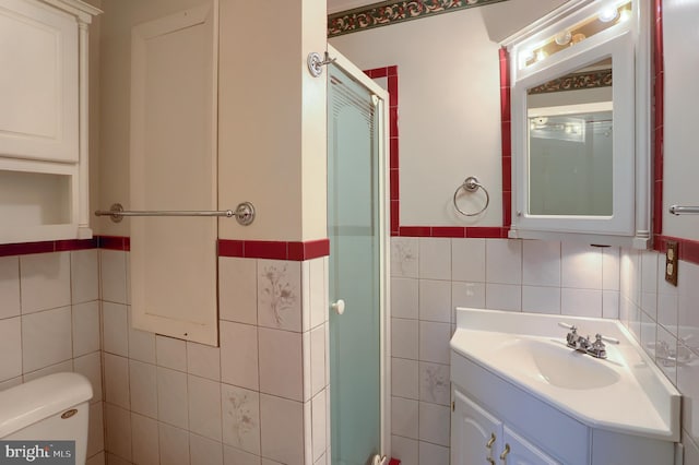 full bathroom with toilet, tile walls, a stall shower, and vanity