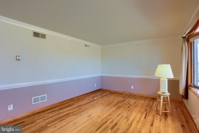 unfurnished room featuring visible vents, baseboards, light wood-style floors, and ornamental molding