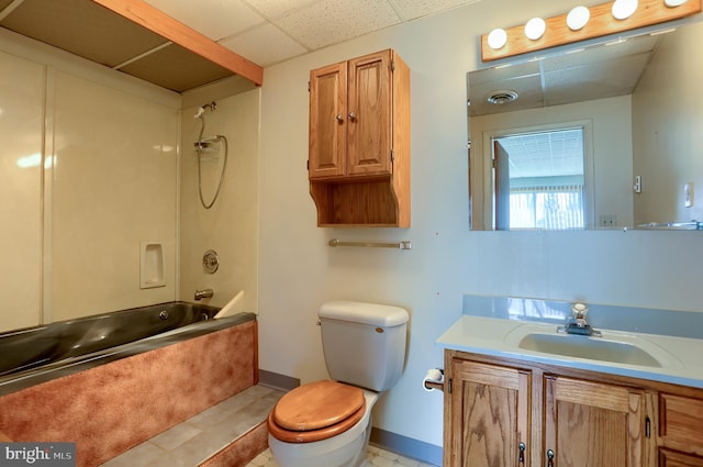 full bathroom with toilet, a drop ceiling,  shower combination, baseboards, and vanity