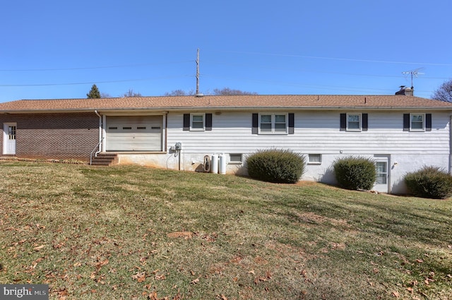 rear view of property featuring a yard and a garage