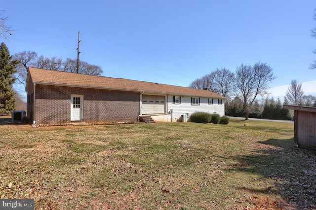 back of house with entry steps, cooling unit, a lawn, and brick siding