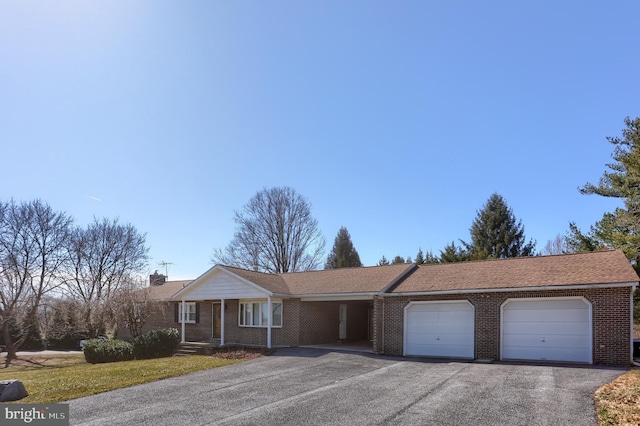 ranch-style house featuring brick siding, a front lawn, aphalt driveway, a chimney, and a garage