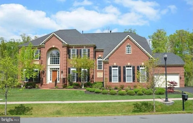 view of front facade with aphalt driveway, a garage, brick siding, and a front lawn