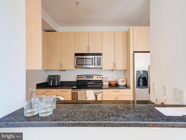 kitchen with dark countertops, light brown cabinets, and stainless steel appliances