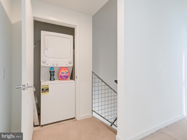 washroom with laundry area, stacked washer / dryer, carpet flooring, and baseboards