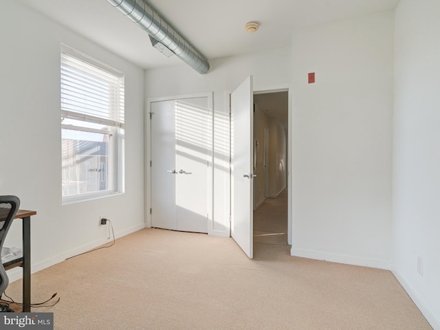 unfurnished bedroom with baseboards and light carpet