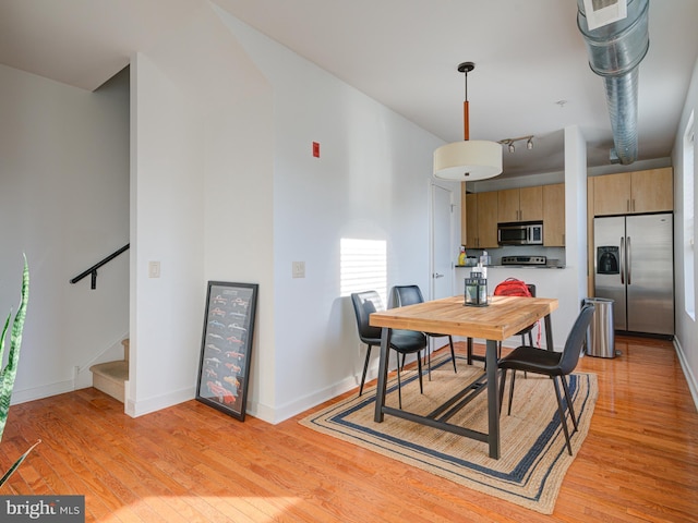 dining space featuring stairway, light wood-style floors, and baseboards