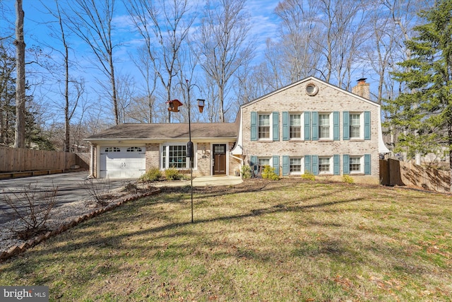 tri-level home featuring brick siding, an attached garage, a front lawn, fence, and driveway