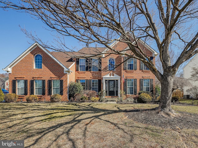 colonial home with brick siding and a front lawn