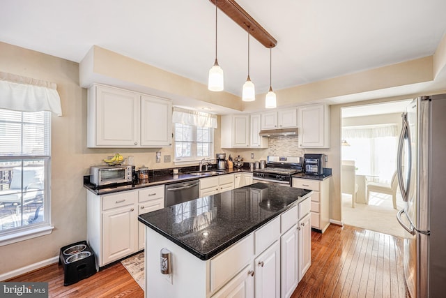 kitchen featuring under cabinet range hood, white cabinetry, stainless steel appliances, and a sink