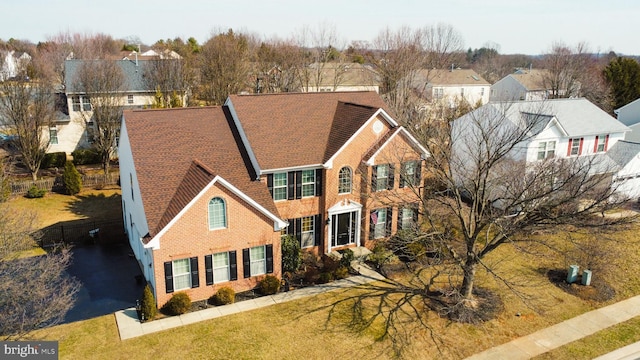 view of front of home featuring a front yard, brick siding, and a residential view