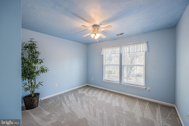 carpeted spare room featuring visible vents, baseboards, and a ceiling fan